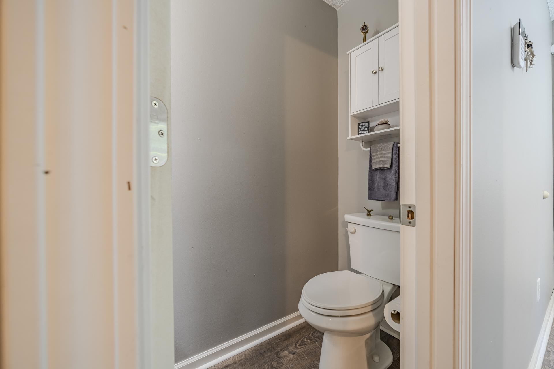 74 Driftwood Road Counce, TN 38326 - Photo 18 of 40 Powder room with wood-finish flooring, neutral gray walls, white trim, and a white toilet