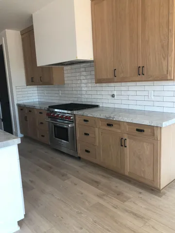 a kitchen with stainless steel appliances granite countertop a stove a sink and white cabinets