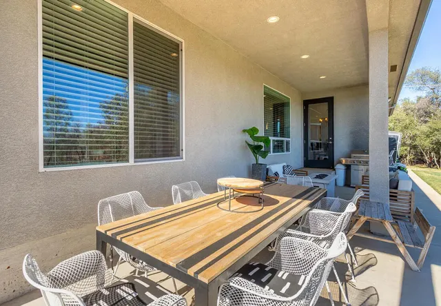 a patio with a table and chairs and potted plants