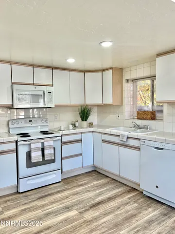 a kitchen with stainless steel appliances granite countertop a stove a sink and white cabinets