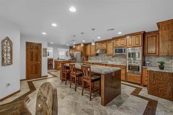 a kitchen with stainless steel appliances granite countertop a table chairs sink and cabinets