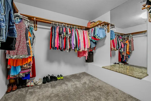a view of walk in closet with clothes and shoes
