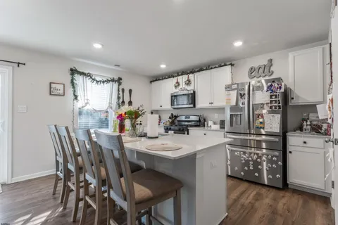 a kitchen with stainless steel appliances a microwave sink refrigerator dining table and chairs