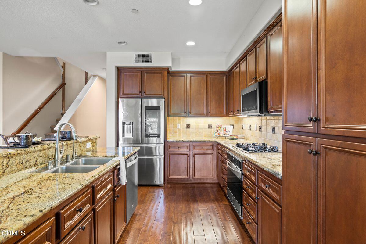 3004 Moonlight Park Avenue Oxnard, CA 93036 - Photo 18 of 28 a kitchen with stainless steel appliances granite countertop a sink stove refrigerator and cabinets