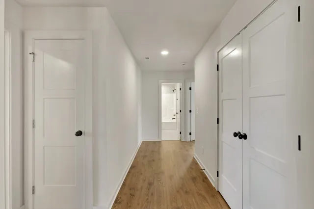 a view of a hallway with wooden floor and closet area
