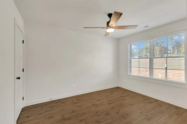 an empty room with ceiling fan and window