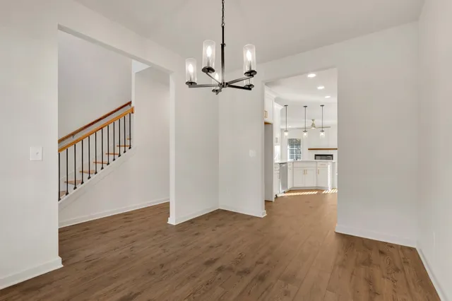 a view of a hallway with wooden floor and a chandelier