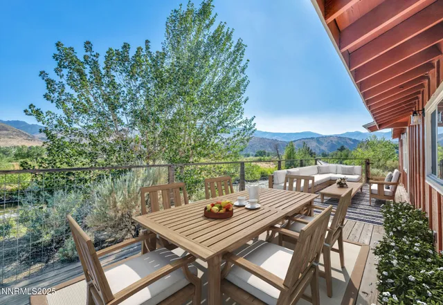 a view of a patio with table and chairs and couches with wooden floor and fence
