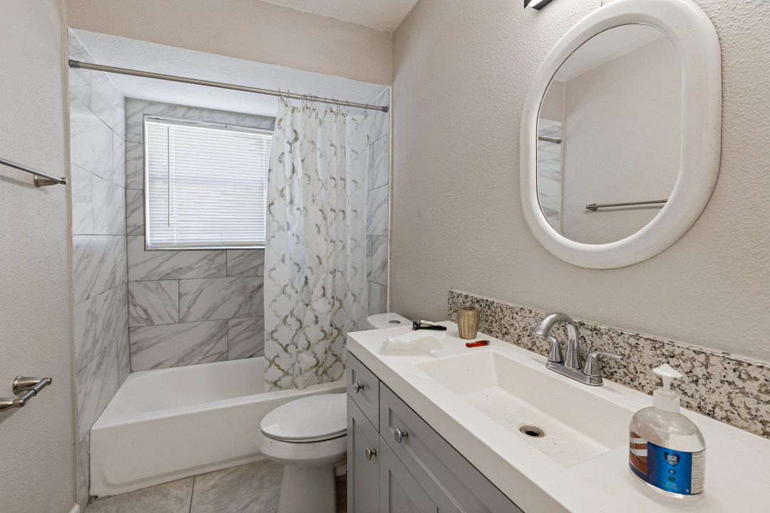 4709 Baton Rouge Street Houston, TX 77028 - Photo 3 of 16 Marble-look tile surrounds the bathtub in this updated bathroom complete with granite vanity tops.