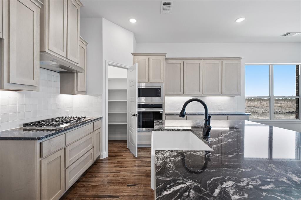 613 Brazos Drive Van Alstyne, TX 75495 - Photo 9 of 29 Kitchen with dark stone countertops, tasteful backsplash, dark wood-style floors, stainless steel appliances, and recessed lighting