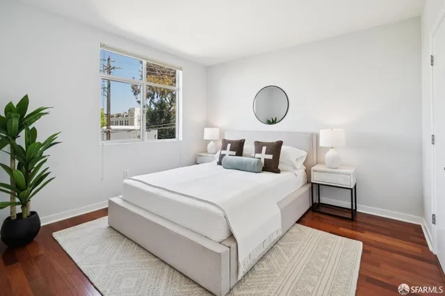 a bedroom with a bed and window with wooden floor