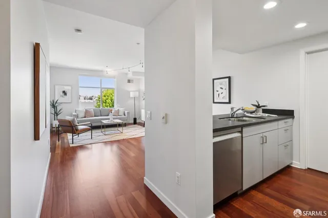 a open kitchen with stainless steel appliances granite countertop a stove top oven a sink a dining table and chairs with wooden floor