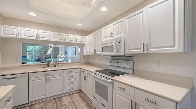 a kitchen with granite countertop white cabinets and white appliances