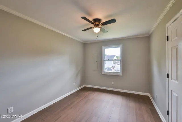 a view of an empty room with wooden floor and a window