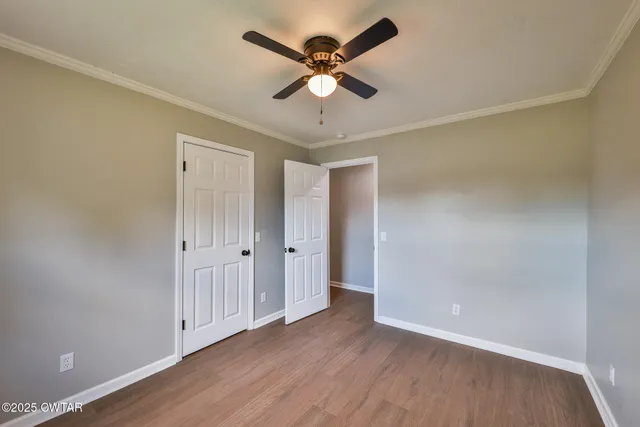 an empty room with wooden floor and ceiling fan