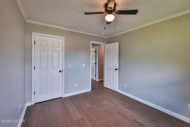 an empty room with wooden floor and ceiling fan