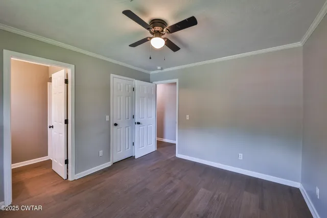 an empty room with wooden floor and ceiling fan