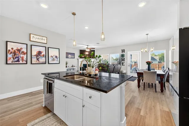 a kitchen with stainless steel appliances granite countertop a stove a sink a dining table and chairs with wooden floor