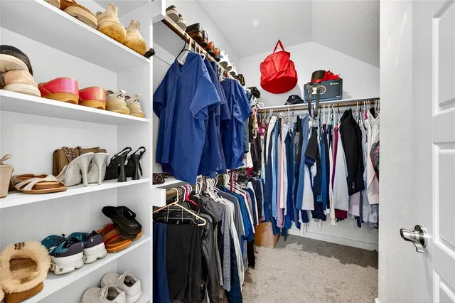 a view of walk in closet with clothes and shoes