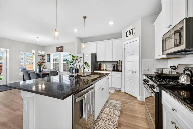 a kitchen with stainless steel appliances granite countertop a sink a stove and a refrigerator