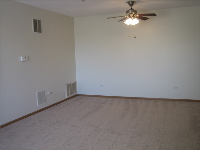 881 Swift Road, Unit 206 Addison, IL 60101 - Photo 5 of 13 an empty room with a chandelier fan and a ceiling fan