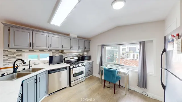 a kitchen with stainless steel appliances granite countertop a sink stove refrigerator and cabinets