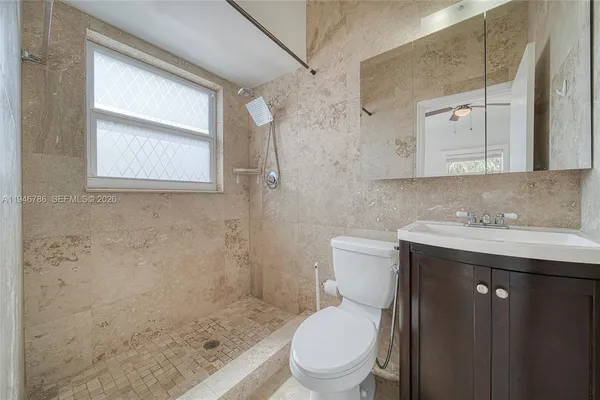 a bathroom with a granite countertop toilet sink and mirror