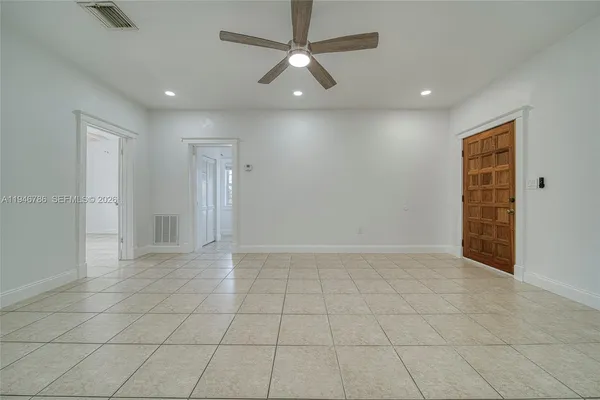 an empty room with white walls and ceiling fan