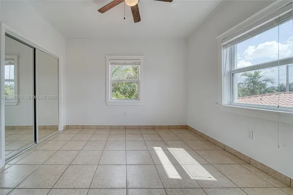 an empty room with windows and fan