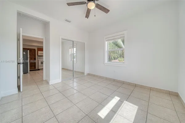 a view of an empty room with window and chandelier fan
