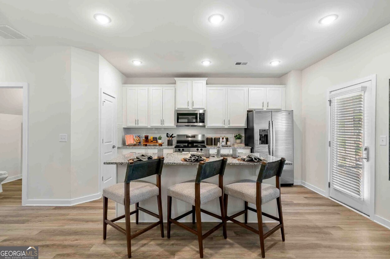 1450 Peachtree Industrial Boulevard, Unit 5109C Sugar Hill, GA 30518 - Photo 2 of 30 a kitchen with a dining table chairs refrigerator and cabinets