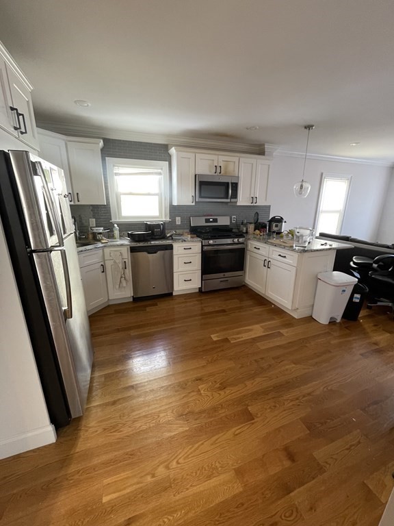 a large kitchen with a stove a sink dishwasher a refrigerator and a stove with wooden floor