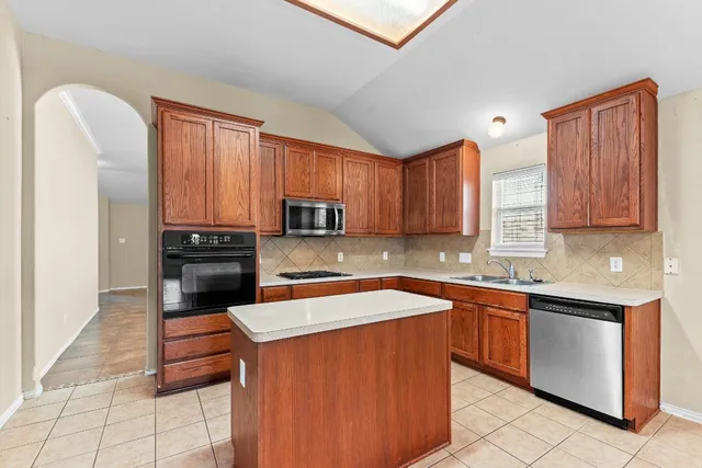 a kitchen with stainless steel appliances granite countertop a sink stove refrigerator and cabinets