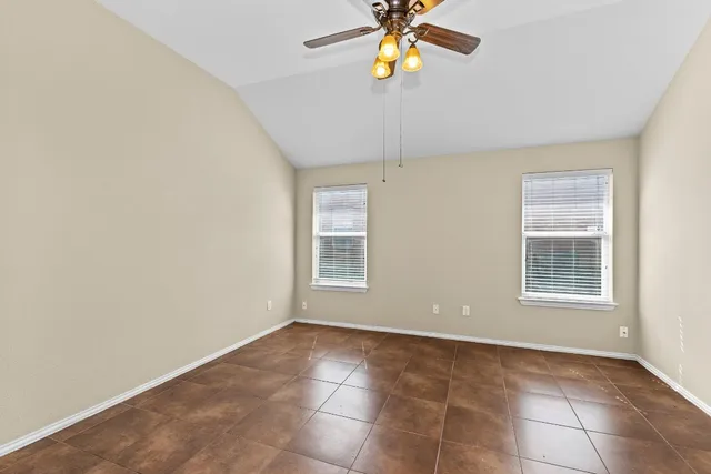 an empty room with a chandelier fan and windows