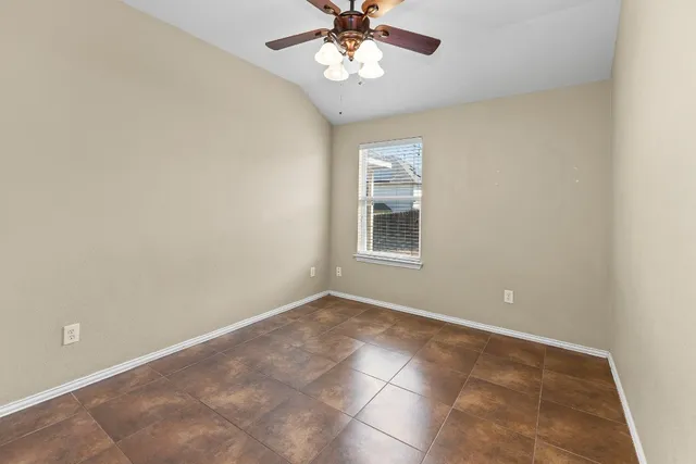 an empty room with a chandelier fan and windows