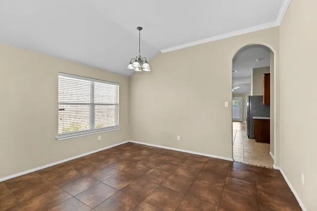 a view of an empty room with window and chandelier