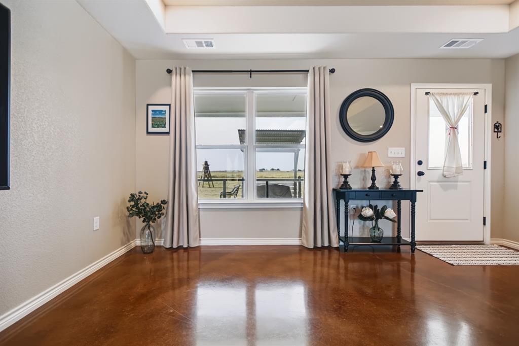 2433 Trlica Road West, TX 76691 - Photo 2 of 40 Tray ceiling, wood-finish flooring, white window trim, white baseboards, and a white paneled door