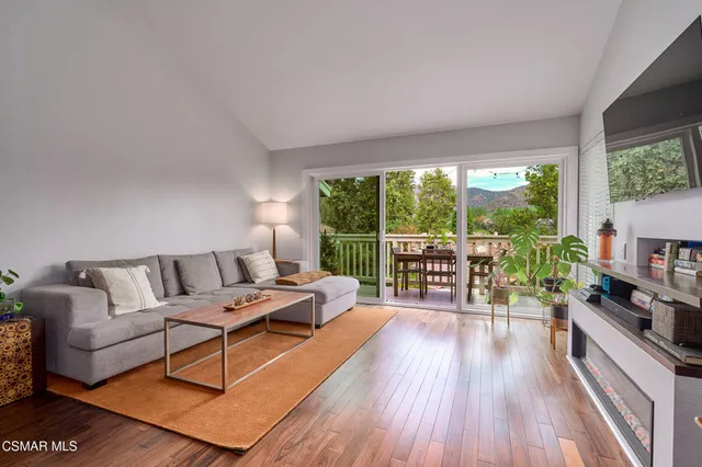a living room with furniture large windows and wooden floor
