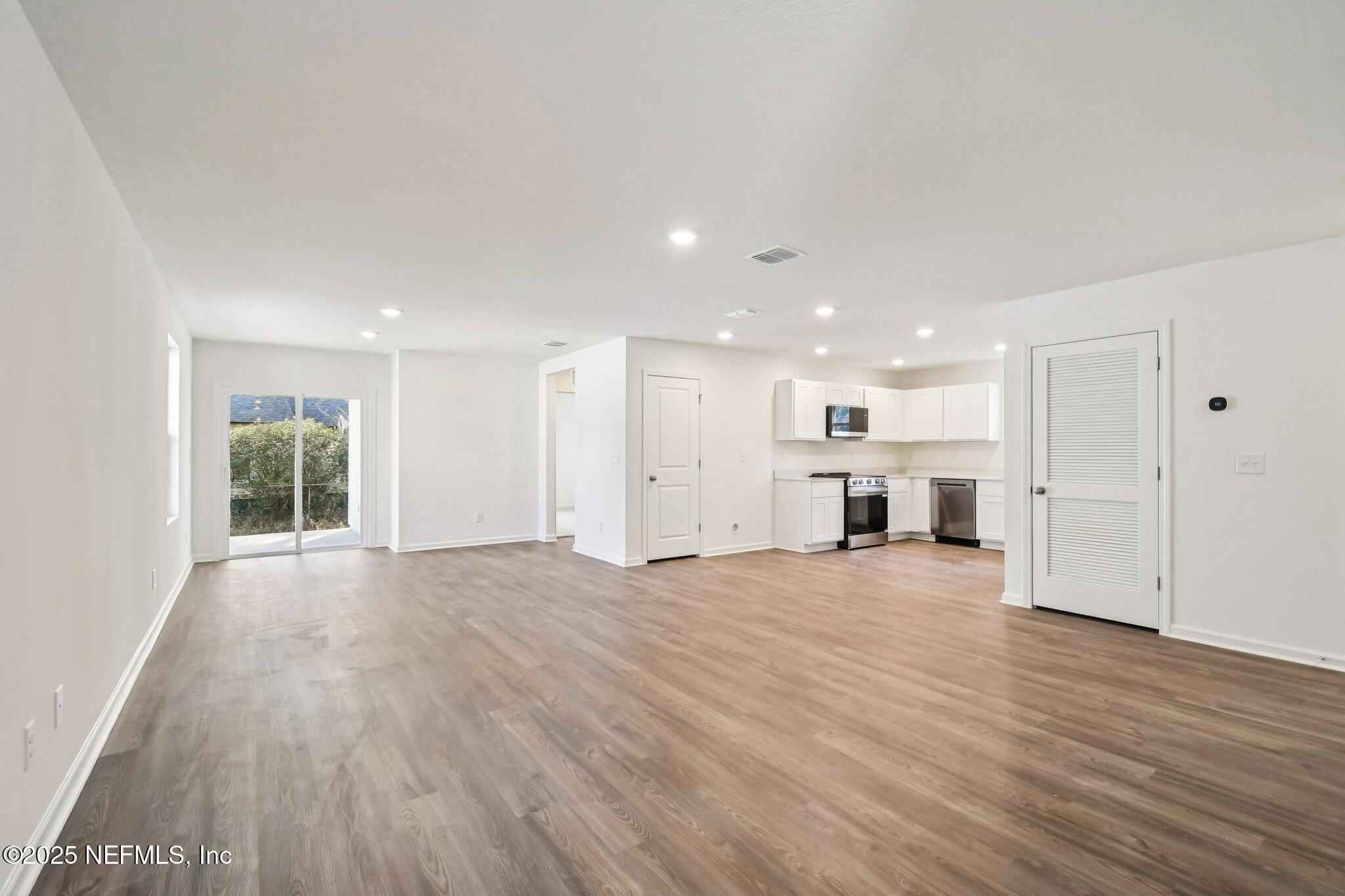3407 Mildred Way Jacksonville, FL 32254 - Photo 15 of 38 a view of an empty room with wooden floor kitchen view and a window