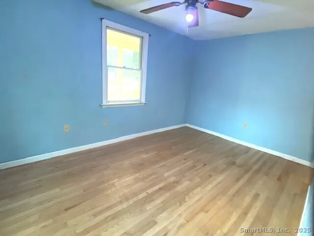 a view of an empty room with window and wooden floor