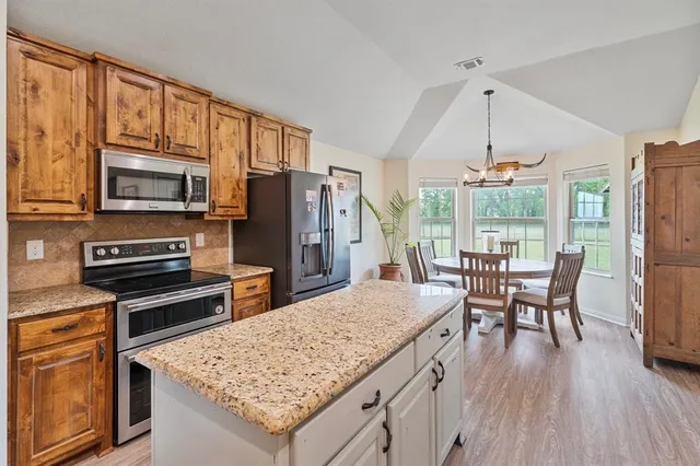 a kitchen with stainless steel appliances granite countertop a kitchen island hardwood floor and a table