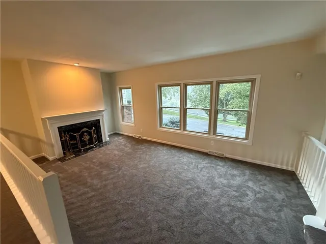 an empty room with windows and fireplace