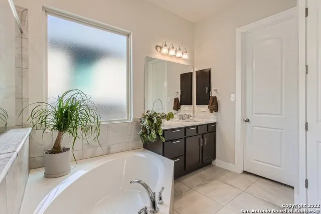 a bathroom with a tub a sink and a mirror