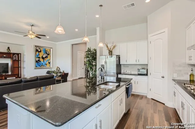 a kitchen with stainless steel appliances granite countertop a sink a stove and a wooden floors