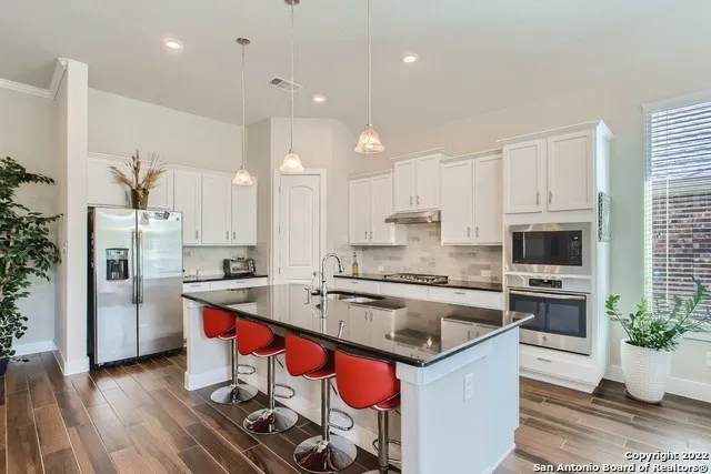 a kitchen with stainless steel appliances a stove a sink a microwave a refrigerator and cabinets