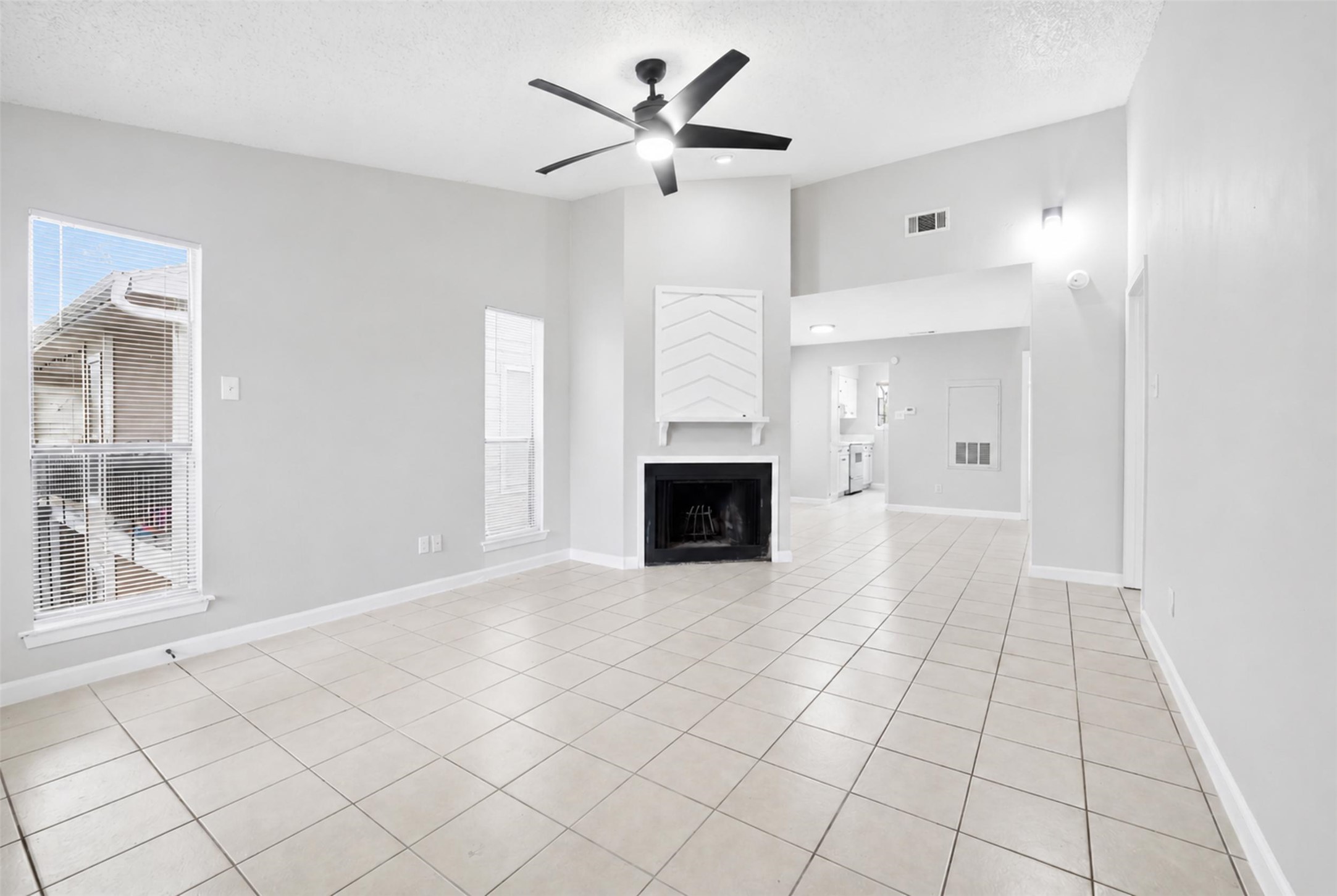 an empty room with windows and fireplace