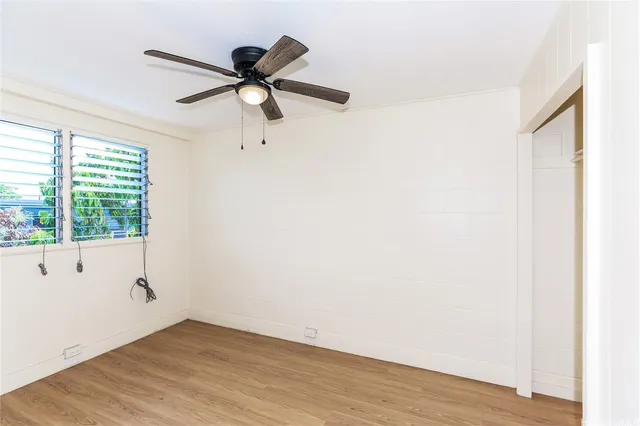 a view of empty room with wooden floor and fan
