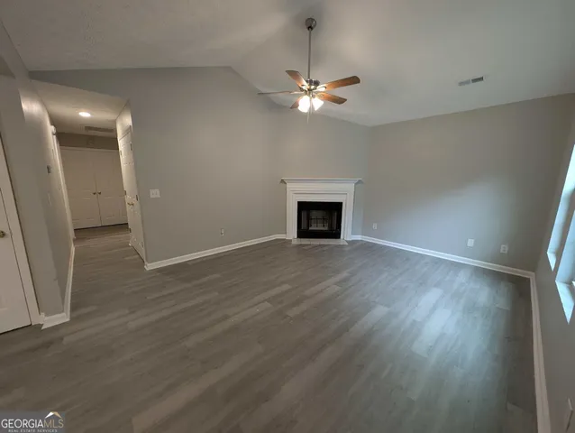 a view of an empty room with wooden floor and a fireplace
