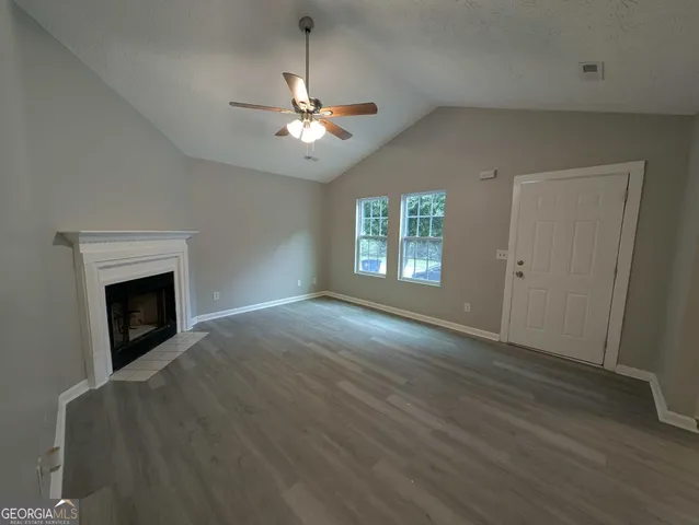 an empty room with windows fireplace and fan