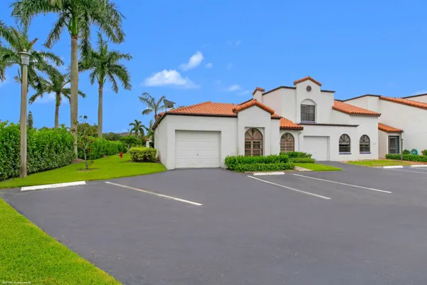 a house with that has a big yard plants and palm trees